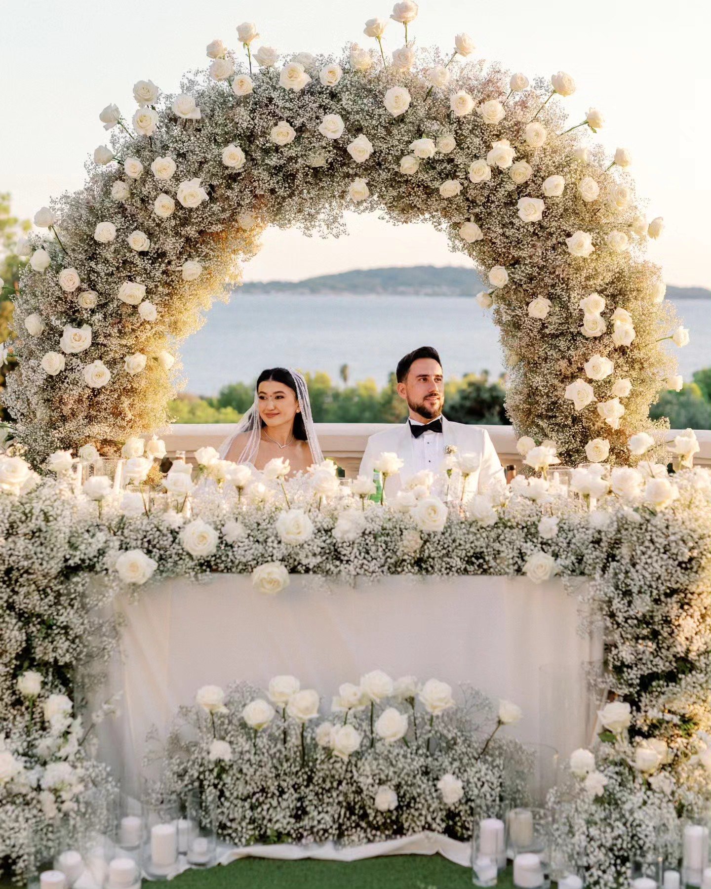Gulnoza et Romain à leur table sous l'arche de roses blanches, face à la mer — Castel Bay