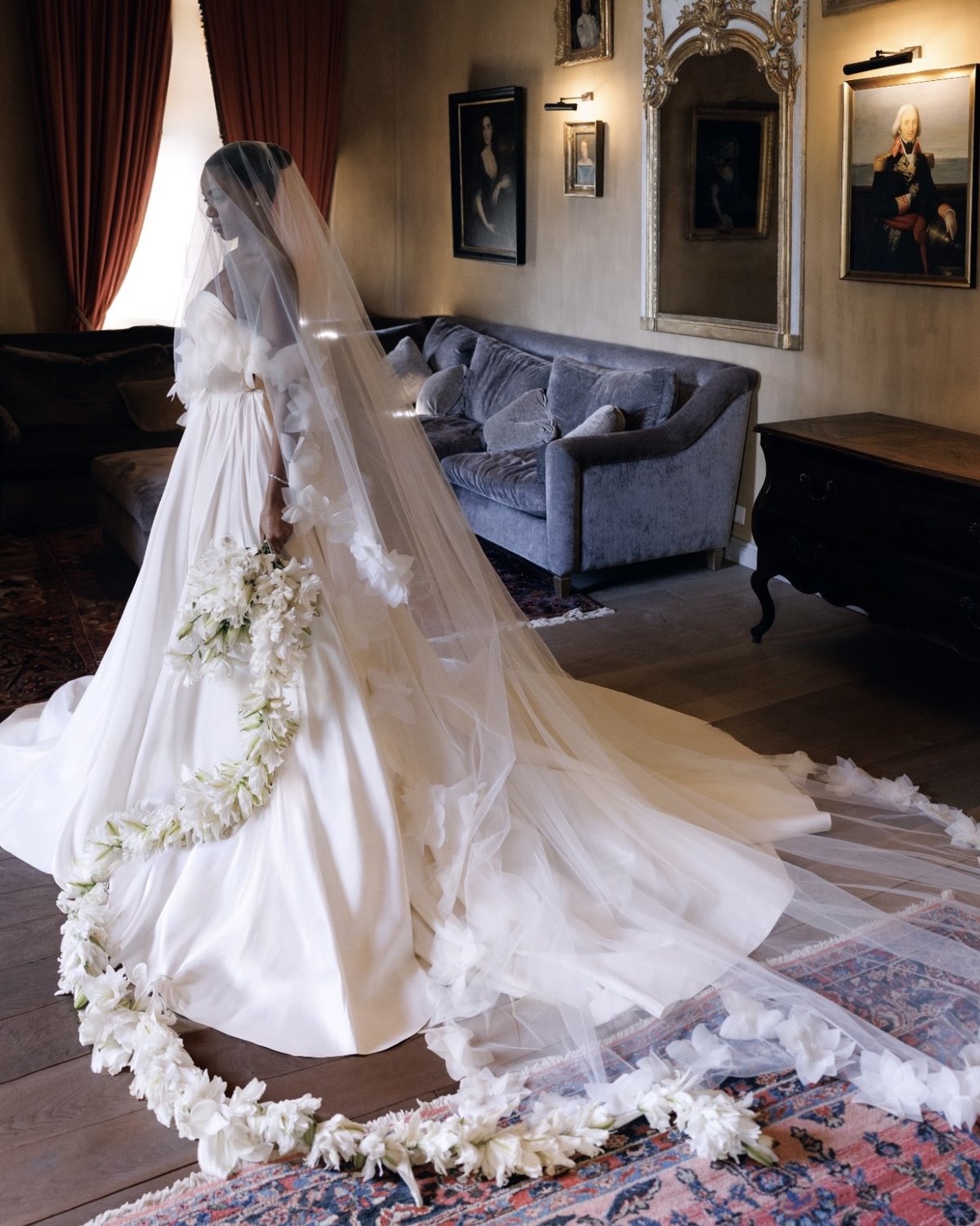 Paris de perfil en el salón del château, con su vestido, un largo velo y una guirnalda de flores blancas