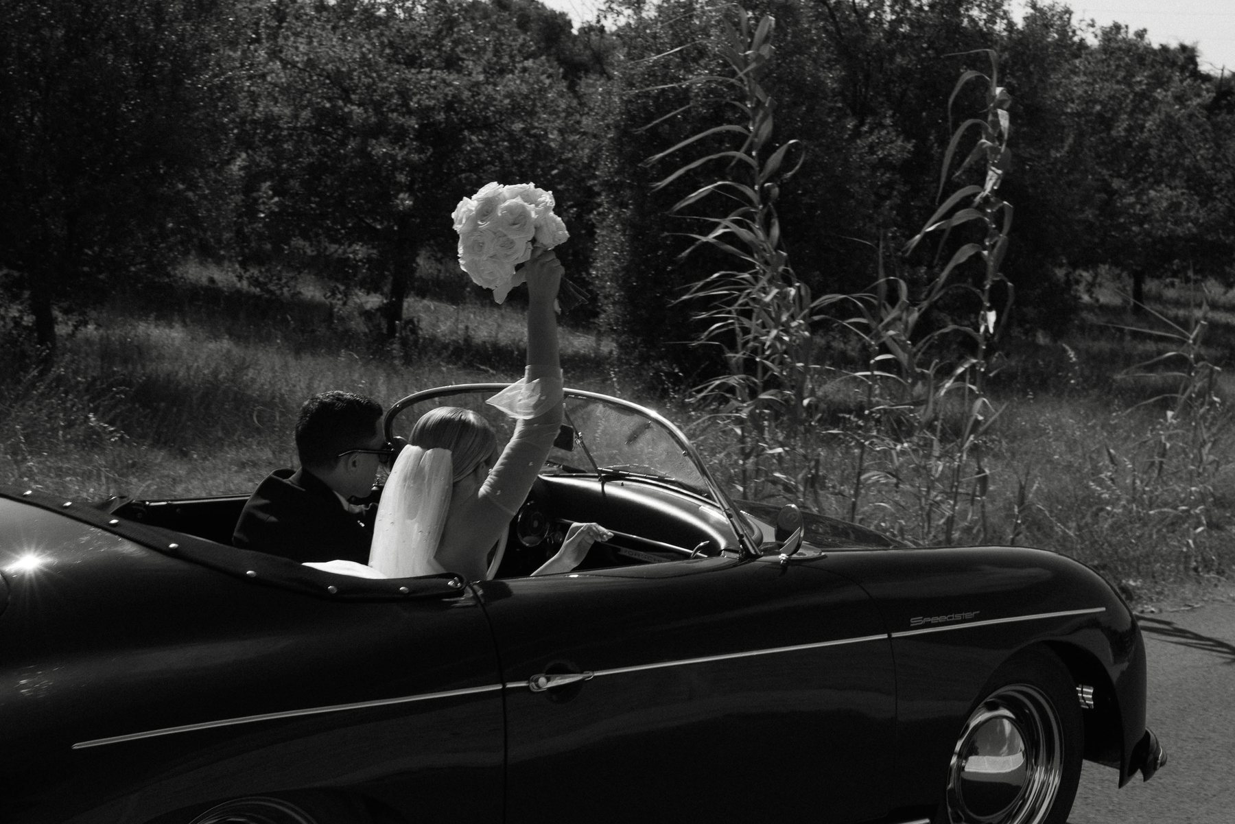 Les mariés en cabriolet, bouquet levé — noir et blanc